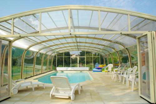 une serre avec une piscine et des chaises autour de celle-ci dans l'établissement La Grimodière Gîte, à Ranville
