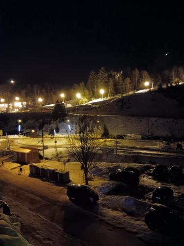 a park at night with snow on the ground and lights at La marmotte in La Bresse
