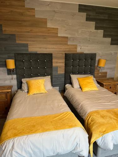 two beds with yellow pillows in a room at Taldrwst farmhouse guest house in Dwyran