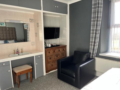 a bathroom with a chair and a sink and a mirror at Taldrwst farmhouse guest house in Dwyran