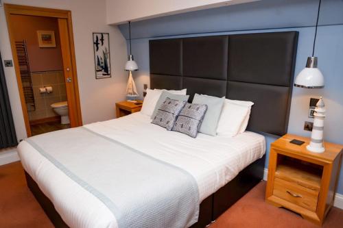 a bedroom with a large white bed with a large headboard at New Wilmington Hotel in Eastbourne