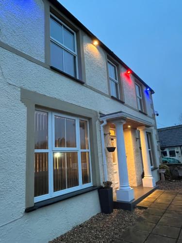 a white house with windows and lights on it at Taldrwst farmhouse guest house in Dwyran