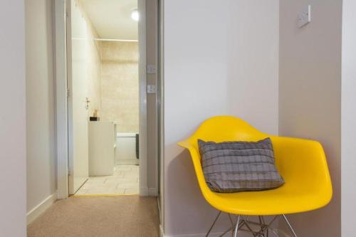 a yellow chair with a pillow on it in a room at The Maltings in Edinburgh