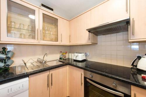 a kitchen with wooden cabinets and black counter tops at The Maltings in Edinburgh
