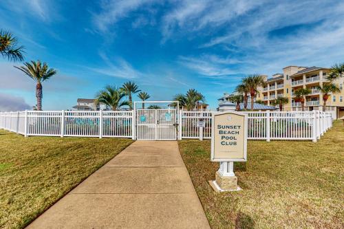 a sign on a sidewalk next to a white fence at Beach Retreat in Galveston