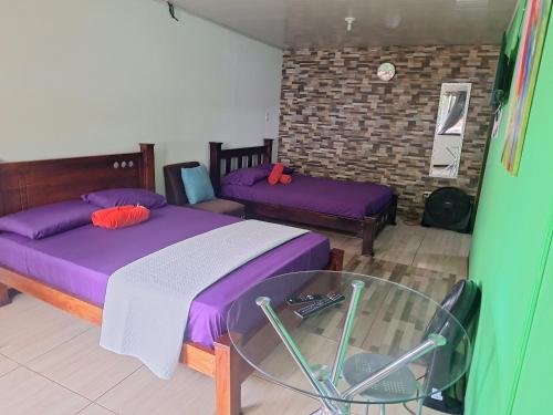 a room with two beds and a glass table at Anchia - Hostel in Alajuela City