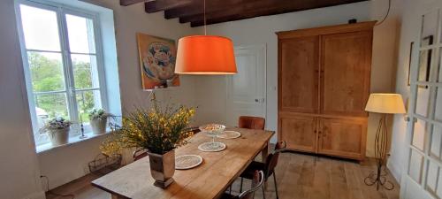 une salle à manger avec une table en bois et des fleurs. dans l'établissement Maison de charme La Vallade, à Ars