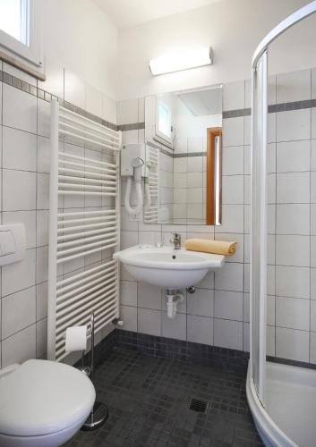 a white bathroom with a sink and a toilet at Hotel Iones in Rimini