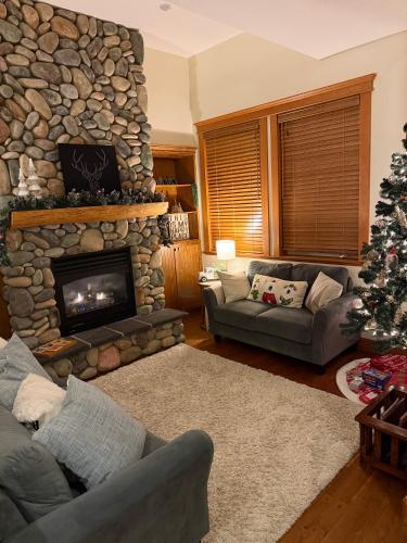 a living room with a stone fireplace and a christmas tree at Gone Ski 'Inn in Big White