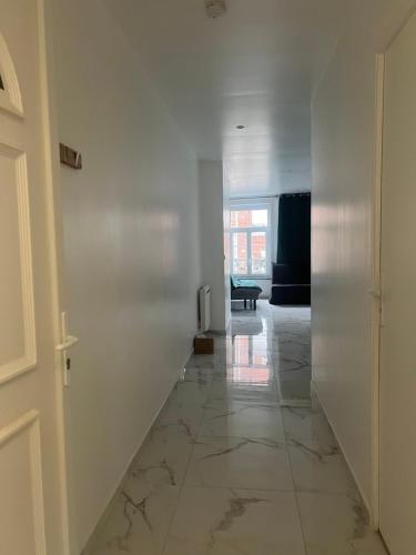 - un couloir avec des murs blancs, un sol en marbre et une porte dans l'établissement Victor 2, à Avesnes-sur-Helpe