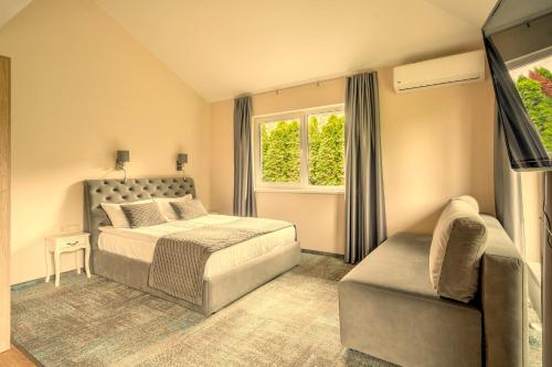 a bedroom with a bed and a couch and a window at Atostogų būstas su jacuzzi in Klaipėda