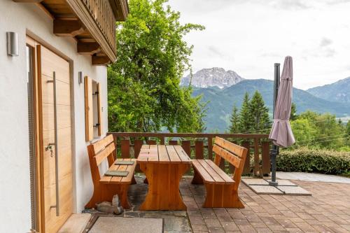 a wooden table and benches on a balcony with an umbrella at Ferienhaus Sonnseitn in Greifenburg