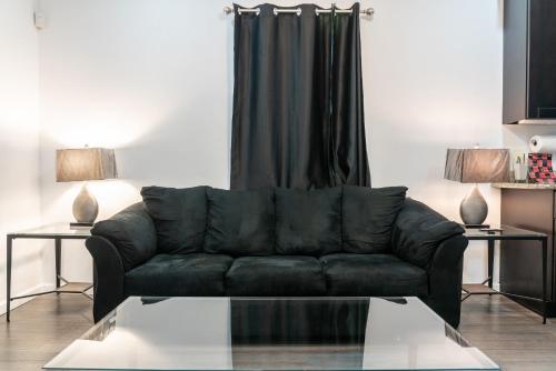a black couch in a living room with two tables at Beautiful Home With Jazucci Tub in New Orleans