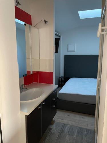 une salle de bain avec un lavabo et un lit dans l'établissement Maison 1 chambre 2 personnes, à Talmont-Saint-Hilaire