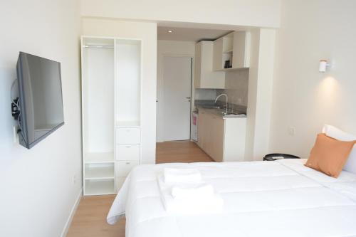 a bedroom with a white bed and a tv on the wall at Torrar Suites in Buenos Aires