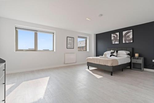 a white bedroom with a bed and two windows at Exquisite 7 Bedroom 5 Bathroom House - Over 1900 sqft - Close to City Centre with Free Parking, Fast W-Fi and SmartTVs by Yoko Property in Northampton