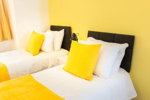 Habitación con 2 camas y almohadas amarillas y blancas. en Charlotte House Spacious 2br 2bath In Ipswich, en Ipswich