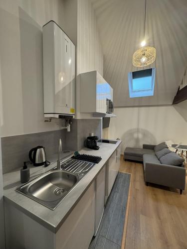 a kitchen with a sink and a couch in a room at Mezza Summer 3ème Étage in Abbeville