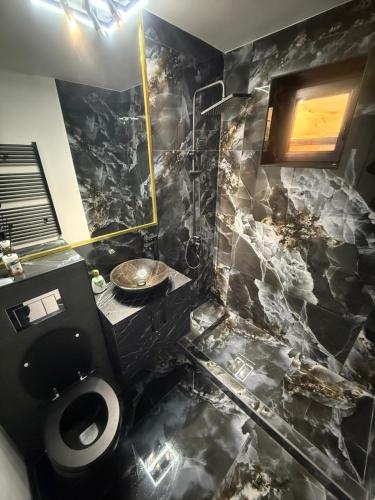a bathroom with a toilet and a black marble wall at Ama Residence in Brăila