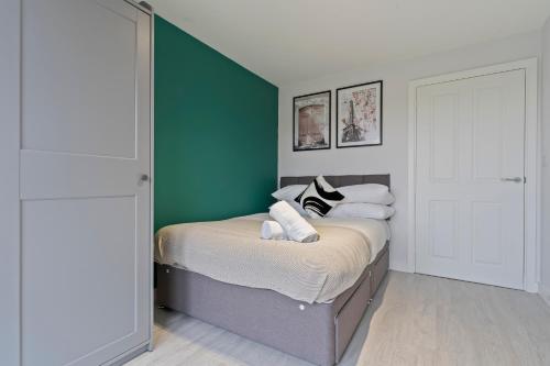 a bedroom with a bed with a green accent wall at Exquisite 7 Bedroom 5 Bathroom House - Over 1900 sqft - Close to City Centre with Free Parking, Fast W-Fi and SmartTVs by Yoko Property in Northampton