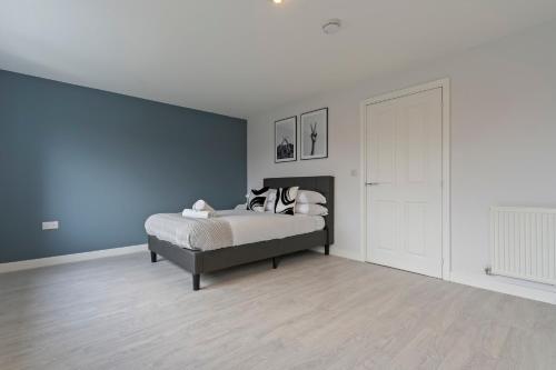 a bedroom with a bed and a blue wall at Exquisite 7 Bedroom 5 Bathroom House - Over 1900 sqft - Close to City Centre with Free Parking, Fast W-Fi and SmartTVs by Yoko Property in Northampton