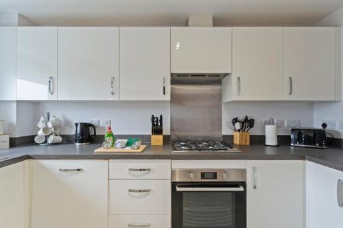 a kitchen with white cabinets and a stove top oven at Exquisite 7 Bedroom 5 Bathroom House - Over 1900 sqft - Close to City Centre with Free Parking, Fast W-Fi and SmartTVs by Yoko Property in Northampton