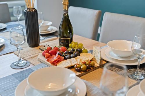 a table with a bottle of wine and a plate of fruit at Exquisite 7 Bedroom 5 Bathroom House - Over 1900 sqft - Close to City Centre with Free Parking, Fast W-Fi and SmartTVs by Yoko Property in Northampton