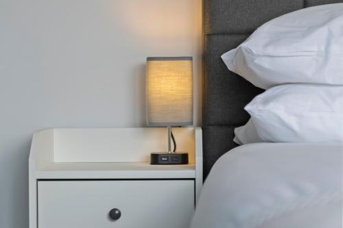 a nightstand with a lamp on it next to a bed at Exquisite 7 Bedroom 5 Bathroom House - Over 1900 sqft - Close to City Centre with Free Parking, Fast W-Fi and SmartTVs by Yoko Property in Northampton