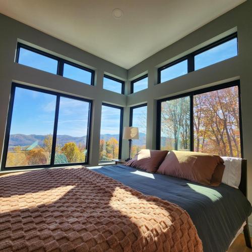 a bedroom with a large bed with large windows at Altitude Adjustment in Nellysford