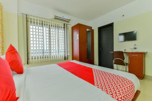 a bedroom with a large bed with a red and white blanket at Super Hotel O Tyche Stays in Trivandrum