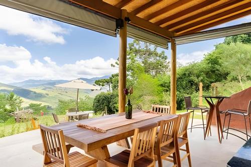 a wooden table and chairs on a patio with a view at Chalés Suítes Gorjeios da Mantiqueira in São Bento do Sapucaí