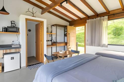a bedroom with a bed and a table at Chalés Suítes Gorjeios da Mantiqueira in São Bento do Sapucaí