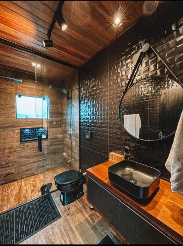 a bathroom with a black sink and a mirror at Refúgio Paraíso Casa Stellato Spa Panorâmica in Orleans