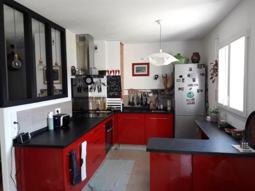 une cuisine avec des armoires rouges et un réfrigérateur dans l'établissement La maison du Bonheur, à Bénesse-Maremne