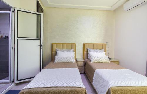 two beds in a small room with a door at Mamora Bay in Tangier