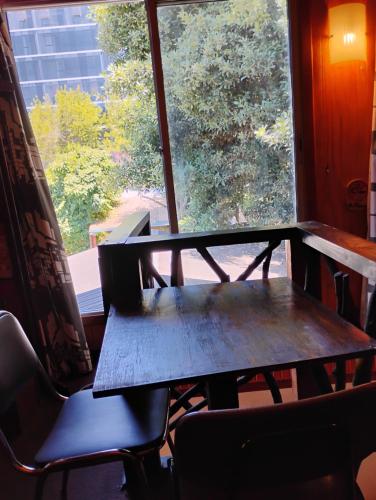 a wooden table and chairs in front of a window at Alta Frontera Hostal in Los Ángeles