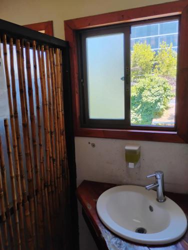 a bathroom with a sink and a window at Alta Frontera Hostal in Los Ángeles