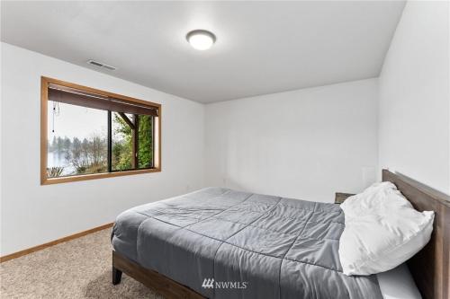 a bedroom with a bed and a window at Beautiful Lake Lodge with Huge Private Dock in Spanaway