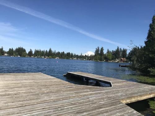 a wooden dock with a bench on the water at Beautiful Lake Lodge with Huge Private Dock in Spanaway