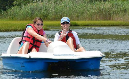 two women are sitting on a raft in the water at Beautiful Lake Lodge with Huge Private Dock in Spanaway