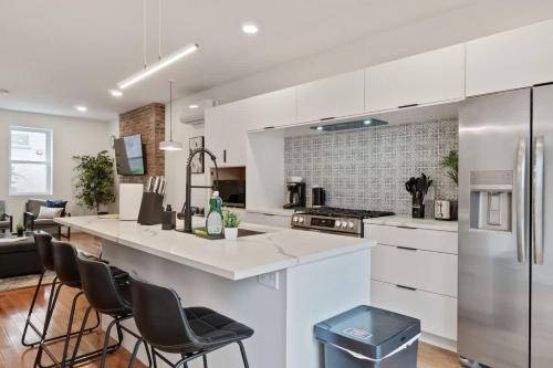 a kitchen with white cabinets and bar stools at Pet Friendly 3 Bdrm House with Private Yard in Pittsburgh