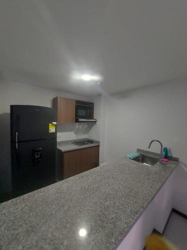 a kitchen with a black refrigerator and a sink at Apartamento Nuevo en el eje cafetero in Dosquebradas