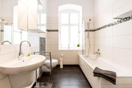 La salle de bains blanche est pourvue d'un lavabo, d'une baignoire et de toilettes. dans l'établissement Apartment Fritz, à Berlin