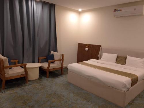 a hotel room with a bed and two chairs at الوعل للشقق الفندقية بالارطاوية in Al Arţāwīyah