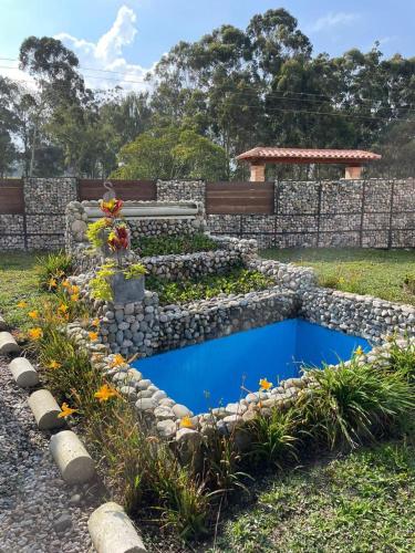 a stone retaining wall with a blue pond in a garden at Mambe refugio in Piedecuesta
