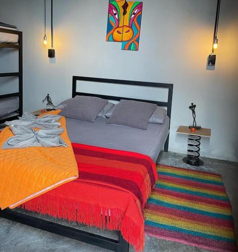 a bedroom with a bed with a red and orange blanket at Mambe refugio in Piedecuesta
