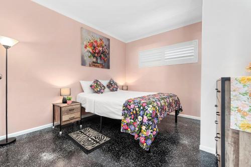 a bedroom with a bed and a painting on the wall at Villa Vaucluse Apartments in Cairns