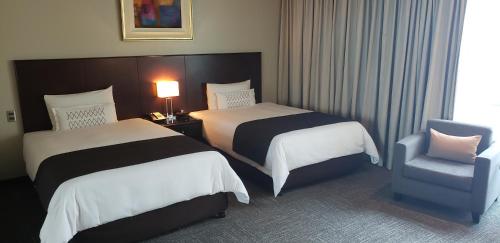 a hotel room with two beds and a chair at Delfines Hotel & Convention Center in Lima