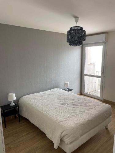une chambre avec un lit blanc et une fenêtre dans l'établissement Appartement lumineux vue mer, à Plouhinec