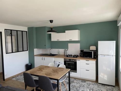 une cuisine avec une table et un réfrigérateur blanc dans l'établissement Appartement lumineux vue mer, à Plouhinec